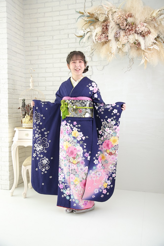 紺地にピンク系の流れるような小花柄をあしらった振袖を着た女性